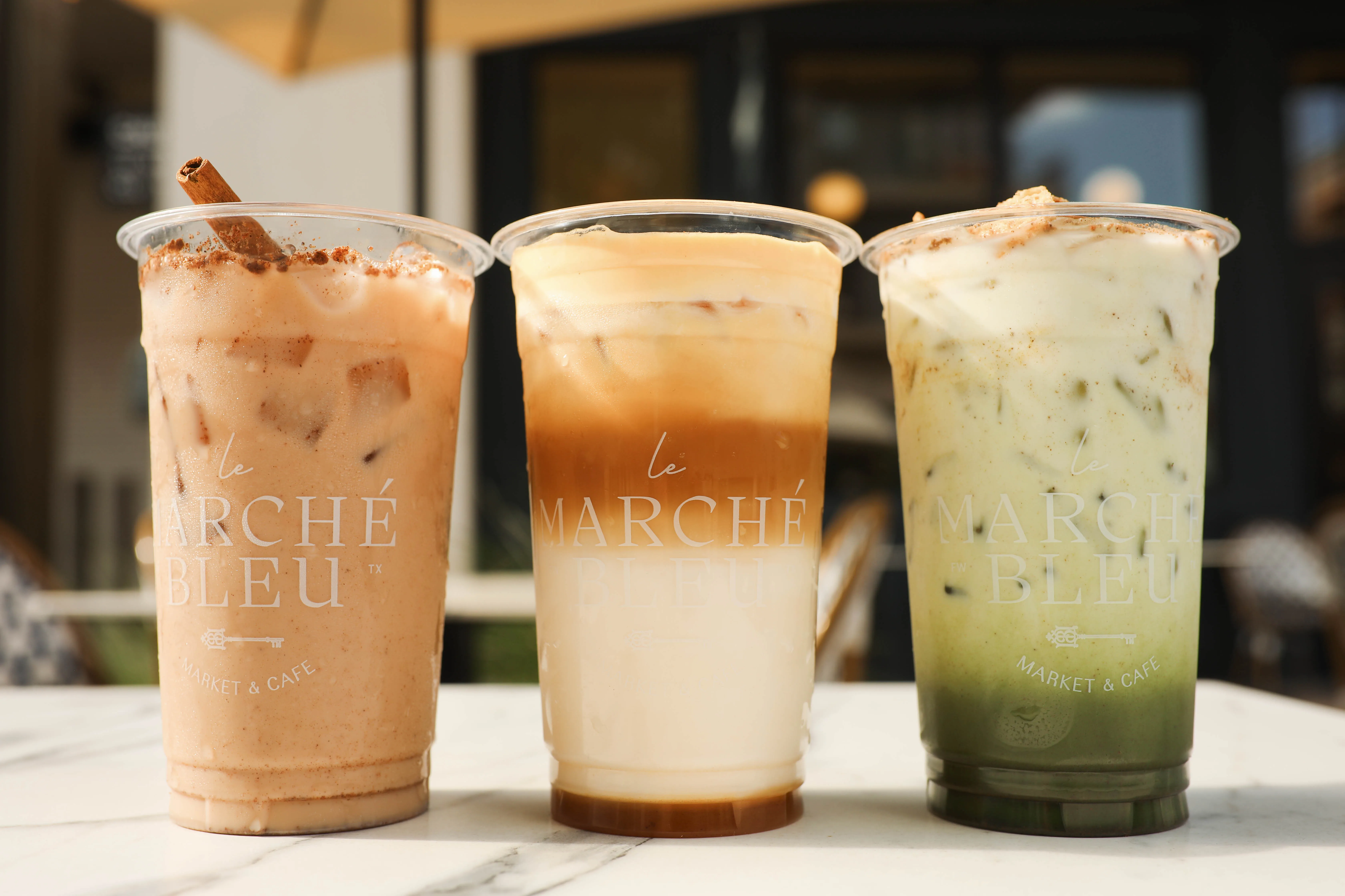 Three signature Marché Bleu iced drinks lined up on a marble table